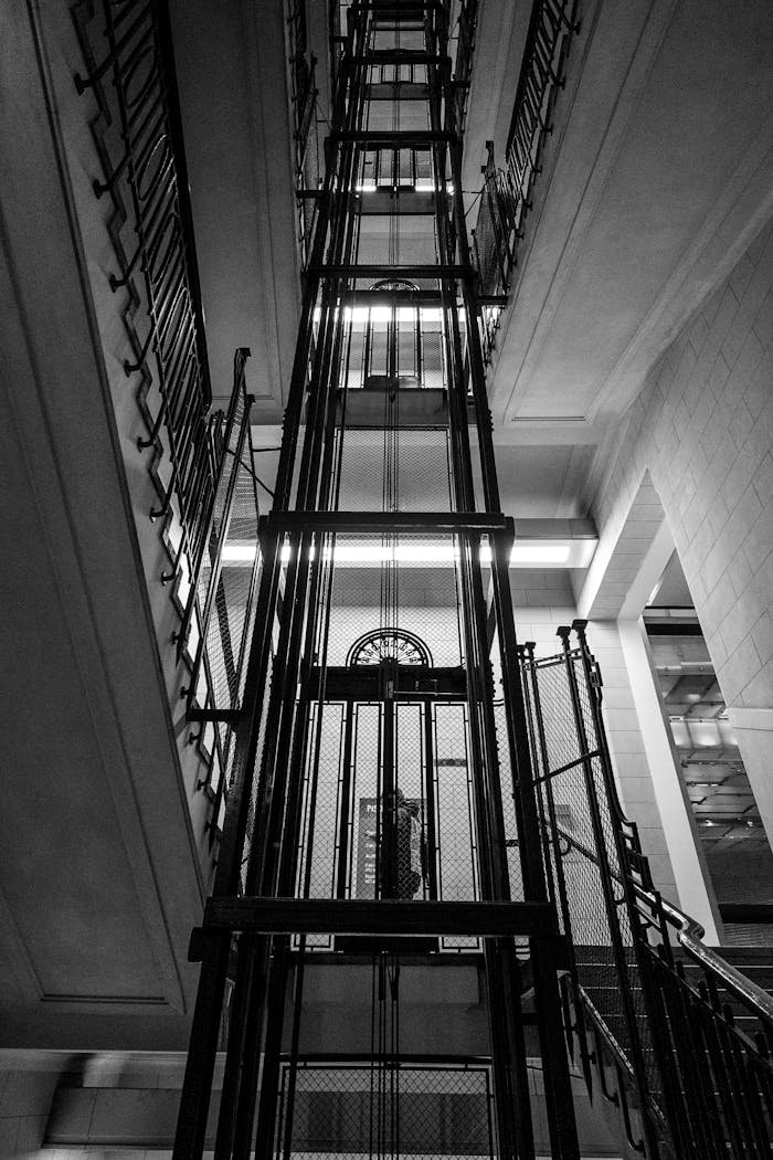 Dramatic black and white view of an antique elevator shaft in a historic building.